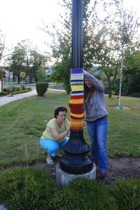 Sherry helping Lisa install her yarnbomb piece on a lamp post.